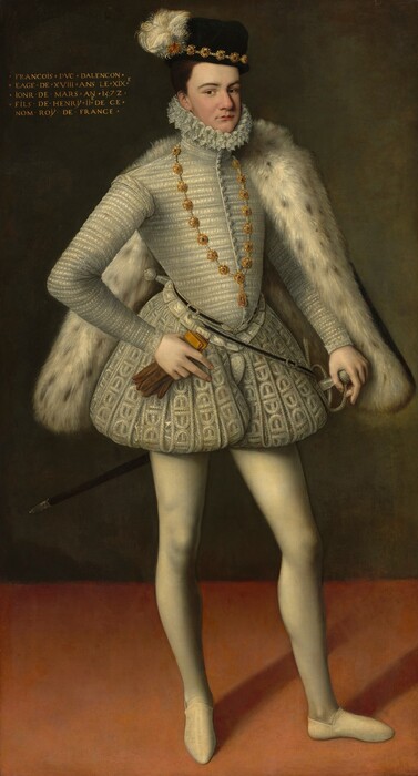 A clean-shaven, pale-skinned man wearing all white, a black-speckled white fur cape, and brimless black hat stands and looks at us in this full-length, vertical portrait painting. The man’s body and face are angled to our right, but he looks at us from the corners of his brown eyes under dark, curved brows. He has a slightly bulbous nose, the suggestion of a cleft chin, and his thin, pink lips are closed. His brown hair is cut short under the cap, which has a high crown. The hat is lined with jeweled gold medallions and pearls around the bottom edge, and the barbs of the white feather flicker like a busy flame. The lace-edged ruff, which is pleated in figure eights, hugs his chin and the back of his neck. The high-collared, white, long-sleeved jacket is textured in narrow, horizontal bands. A narrow black belt decorated with silver trim and pearls loops around his waist, and a sword hangs from the far hip. The white-on-white patterned breeches puff out at the waist and are gathered high on the thigh, like puffy shorts. He wears smooth, cream-white stockings and the same color slippers. The hip-length fur cape hooks over the far shoulder, and that hand rests on the pearled hilt of a thin sword. His other elbow is bent, and he holds a pair of gold and brown-colored gloves in that hand. The first two fingers are extended to lie along the fabric of his pants. The wall behind the man is earthy green and the floor a rosy peach. Gold text in the upper left corner of the painting reads, “FRANCOIS DVC DALENCON EAGE DE XVIII ANS LE XIXE IONR DE MARS AN 1572 FILS DE HENRŸ II DE CE NO ROŸ DE FRANCE.”
