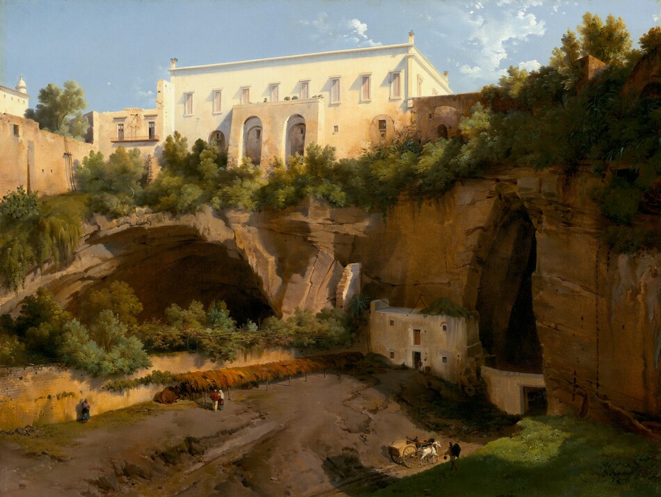 This painting shows a white and tan building on the edge of a rocky cliff, seen from slightly below. There are arched openings within the cliffside, with some other small buildings tucked into them. The ground is brown and covered with leafy greenery on the top of the cliff and in a cave on the left, with a patch of green grass in the bottom right corner. In the center, distant people and a horse-drawn cart walk on a path below the cliff, towards one of the openings. The sky above is blue with scattered white clouds.