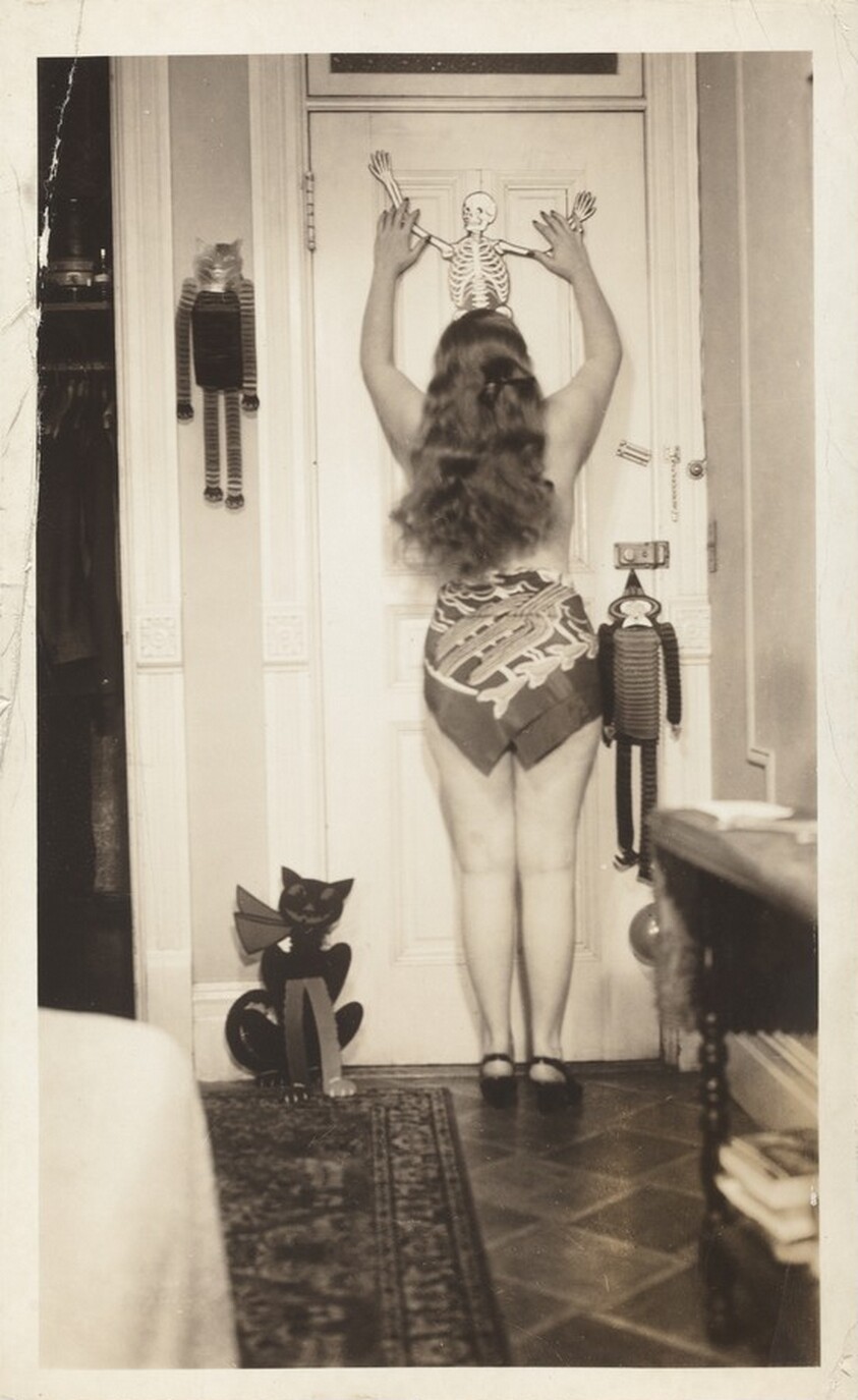 Untitled (Woman posed from behind against door with hanging skeleton)