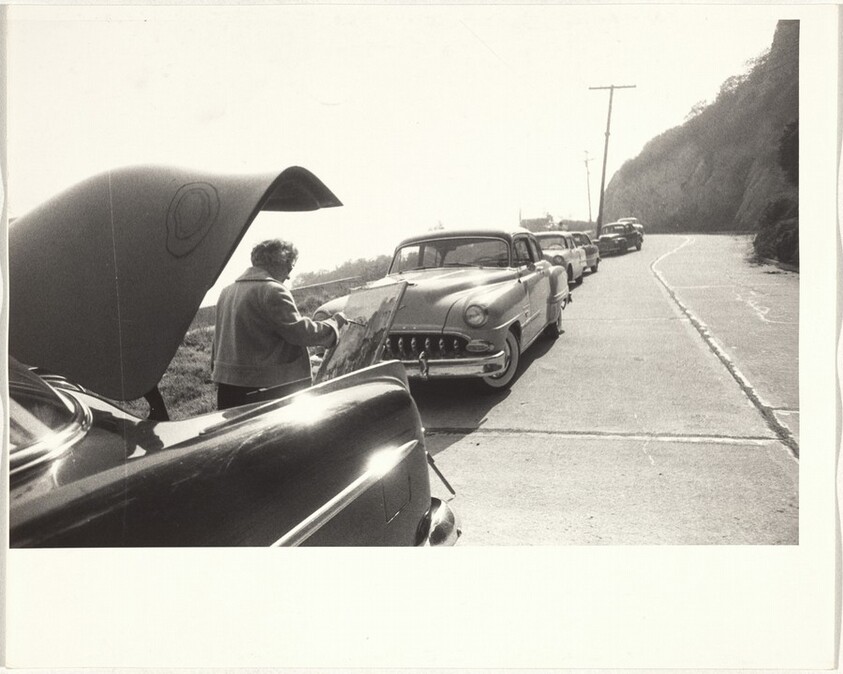 Woman painting beside parked automobiles--Los Angeles