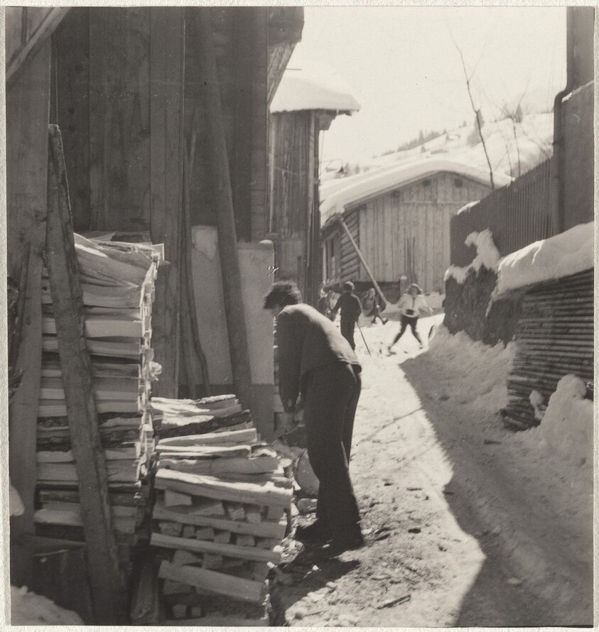 Man stacking wood with skiers in background--Sports