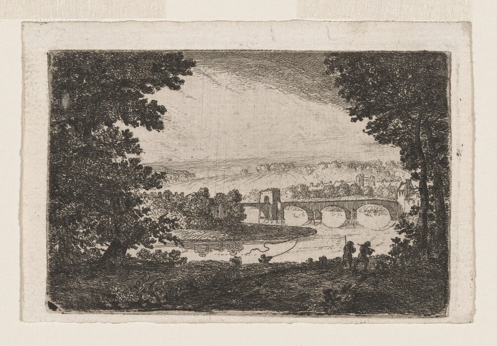 The image shows a landscape scene with two large trees framing the view. A bridge crosses a calm body of water in a town, with buildings and trees in the distance. Hills roll upward towards a sky. There are two small figures standing to the right. The scene uses a monochromatic color palette with black, grey, and white, typical of an etching technique with fine lines and cross-hatching for texture and depth.