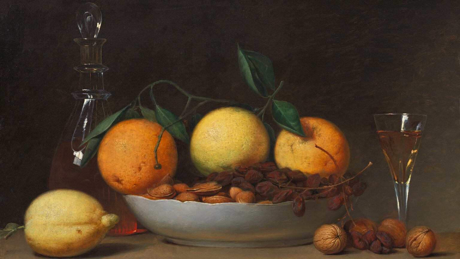 A shallow bowl filled with oranges, grapes, and nuts is surrounded by a short, flaring glass, a glass decanter, a lemon, and more nuts arranged along a wooden tabletop in this horizontal still life painting. The objects nearly fill the composition, and the table extends off both sides. The three oranges are pale, with the one at the center nearly yellow, and a stem of dark green leaves lies across the top. A bunch of shriveled grapes, like raisins still on the vine, lies across the almonds and other nuts, all in their shells, in the bowl. The outside of the bowl is white, and it has a gently scalloped rim. A lemon sits to our left of the bowl of fruit, and behind it, the glass decanter has a teardrop-shaped glass stopper. Light coming from the front and our left makes the peachy liquid glow. To our right are four whole walnuts in their shells, with a few grapes hanging from the bowl. Behind the walnuts, a long stemmed, flaring, clear glass is almost filled with the peach-colored liquid. The background is deeply shadowed at the upper left, lightening slightly to elephant gray toward the lower right. The artist inscribed the painting as if he had written his name, date, and location on the front edge of the table, near the lower right corner: “Raphaelle Peale Aug: 5th 1814 Philad:”