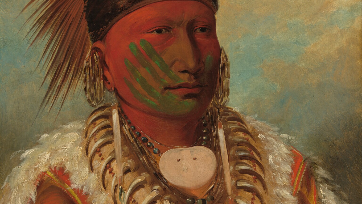 This vertical portrait shows the head, shoulders, and chest of an indiginous Iowan man with brown skin whose face is mostly painted with red and green. His body and face are angled to our right and he looks into the distance with dark eyes. Crimson-red paint covers his forehead, the sides of his cheeks, and neck. Four parallel lines of pine green angle up his right cheek, on our left, like the four fingers of a hand. A green line on the other cheek could be the thumb, and the palm might have left the green mark on his chin. The man’s nose and cheeks near the nose are unpainted. His spiky headdress is ornamented with two feathers and is held in place with a wide band of dark fur that wraps across his forehead and around the back of his head. Earrings hang from the lobes and tops of his ears, and he wears a necklace made up of bear claws, beads, and seashells, including an oval shaped, medallion-like shell at his throat. His garment is made up of white fur and what appears to be tawny-brown animal hide. Tan-colored clouds create a screen across an ice-blue sky in the background.