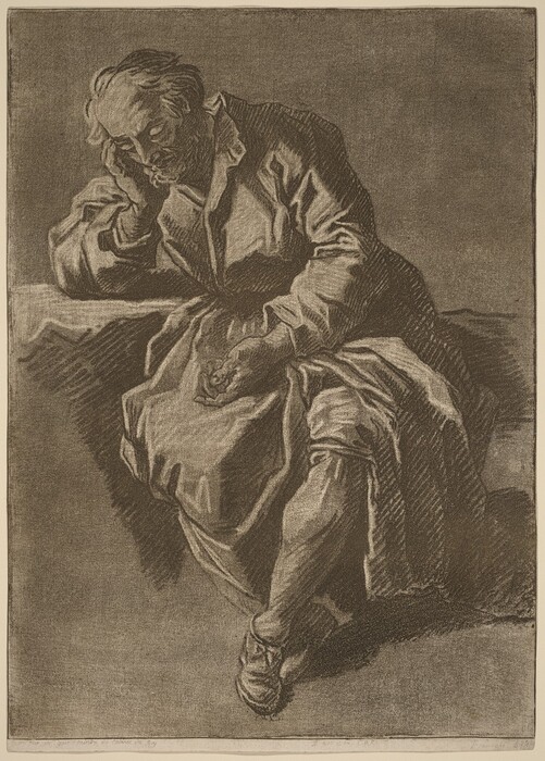 The image depicts an elderly man from the waist up in a seated position. He is leaning forward, resting his left elbow on a surface while supporting his head with his hand. His eyes are closed, and he has a prominent beard and mustache, with thinning hair that recedes from his temples. The man is wearing a robe-like garment that covers his body, featuring a draped fabric that falls into soft folds. His other hand rests on his leg, open-palmed. The background is a plain, textured surface that gives depth to the image, with the edges of the garment and surface providing contrast against the backdrop. There are no visible objects or jewelry in the composition.