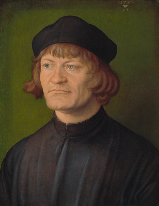 Shown from the chest up, a pale-skinned, clean-shaven man looks off to our left against a moss-green background in this vertical portrait painting. The man’s shoulders and face are angled to our left, and he looks up and in that direction with silvery-blue eyes under flat, thin brows. The end of his short nose is slightly flattened, and his thin, pale pink lips are pressed together in an uneven line. He has the suggestion of a cleft chin set in a square jaw. Auburn-brown, wavy, chin-length hair and bangs frame his face under a black floppy cap. His dark garment has a high neck and falls in vertical folds down his chest. The earthy green background darkens around the edges. The artist signed and dated the painting, 1516, near the top right corner with a monogram of a capital letter D tucked between the wide, long legs of a capital A.