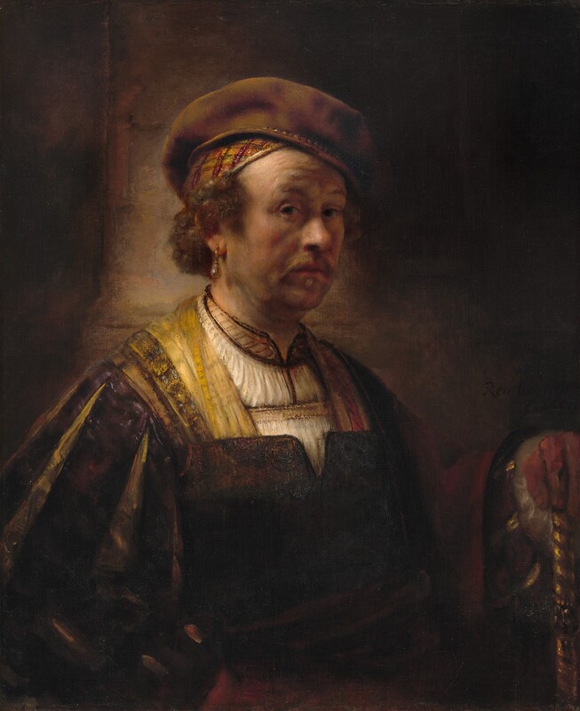 Shown from the waist up, a man dressed in fine clothing looks out at us from against a deeply shadowed background in this vertical portrait painting. The man’s pale, peachy skin has a warm undertone that glows in a stark light source from our left. His body and face are angled to our right, and he cuts his dark eyes back to look at us under raised brows. He has a rounded, bulbous nose, and a wispy golden-brown goatee frames his closed pink lips. Shadows on his cheeks and jowls suggest soft flesh and a five o’clock shadow. Wiry brown hair curls out over his temples and down to the nape of his neck beneath a green, gold, orange, and burgundy-red skullcap. A soft brown beret rests on top of his skullcap tipped at an angle away from us. A teardrop-shaped pearl earring hangs from a gold setting in the ear we can see. He wears a cream-white tunic with gold and brown detailing along the hemlines. Over that is a dark brown, vest-like garment. The sleeves are slashed so the outer fabric is eggplant purple, and the inner slashes are golden yellow. A red cloth drapes over his left arm, farther from us, and that hand rests on a gold, spiraling shaft. A dark sash may be tied around his waist, and it seems that his other hand rests against his hip, to our left. The lower half of his chest and the background fall into deep shadow, though, so some the details there are difficult to make out. The painting is signed and dated in dark letters in a shaded area, so is nearly invisible in the lower center right; it reads, “Rembrandt f. 1650.”