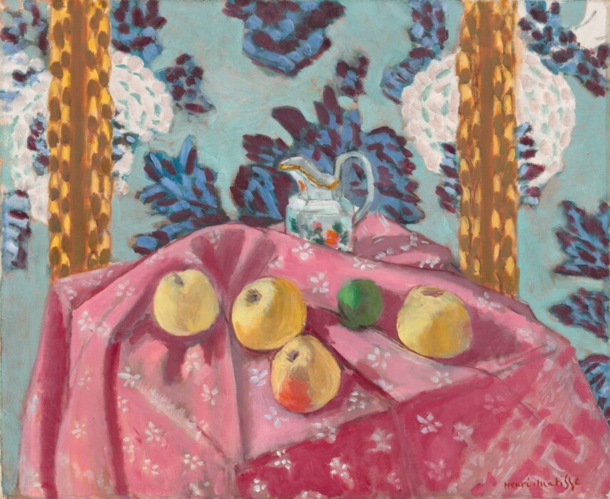 Four yellow apples, a lime, and a ceramic pitcher are loosely arranged across a tabletop covered with a carnation-pink cloth patterned with white flowers in this almost square, stylized still life painting. The scene is loosely painted with visible brushstrokes in saturated colors throughout. We look slightly down onto the front corner of the table, where the canary-yellow apples sit in the folds of the tablecloth. The apple closest to us at the corner of the table has a scarlet-red patch on the side facing us. Between the two rightmost apples, the lime is painted in shamrock and fern green. The cloth is bunched up just behind the apples to partially obscure the pitcher sitting near the back of the table. The pitcher is painted with swipes and patches of white, aquamarine blue, and silver gray with gold highlights along its spout. Daubs of pine green, rose pink, and flame red suggest a floral decoration on its side. The wall beyond the table fills the height of the composition, and is scattered with white flowers layered over an aquamarine-blue background. The blossoms seem oversized, each the size of a blown-up balloon. Other leafy forms painted with sapphire blue and plum purple could be more flowers or leaves. Two vertical stripes to the left and right behind the table are made up of strokes and daubs of caramel brown over honey yellow. The artist signed the lower right, “Henri-Matisse.”