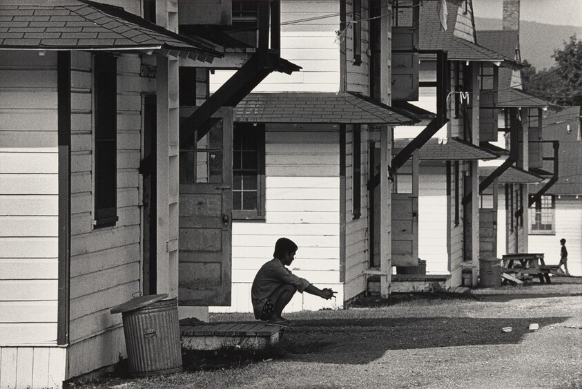 Refugee squatting on porch of barracks