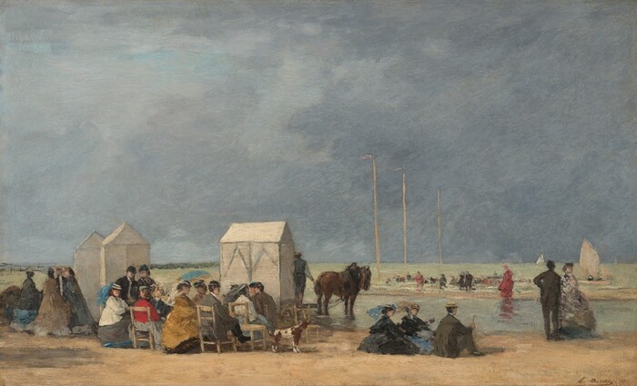 About two dozen men and women sit in straight-backed, wooden chairs gathered along a sandy expanse around pockets of water under a slate-blue sky that fills the top two-thirds of this horizontal landscape painting. Most of the people sit with their backs to us but the faces we can see suggest they all have light skin. The people gather in a loose crowd that crosses the left two-thirds of the composition. The women wear dark hats and long dresses with full skirts, their shoulders wrapped in shawls in black, red, dark yellow, or cream white. The men also wear hats, most of them black bowler hats, and suits in black or pecan brown. A few women hold up blue parasols in harvest gold, slate blue, teal, or gray. Two women and a man sit on the sand to the right. Three changing huts stand behind the group across the left half, and two brown horses stand at the water’s edge nearby. Three poles march into the distance to the right near where more people gather across a pocket of water. The artist signed and dated the lower right corner, “E. Boudin – 65.”
