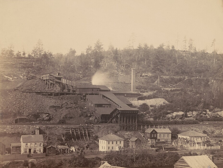 The image shows an industrial scene with a factory complex on a sloped terrain. A line of trees marks the horizon, with residential-style buildings clustered below the industrial structures. The sepia-toned image has detailed brushstrokes capturing the texture of the surroundings.