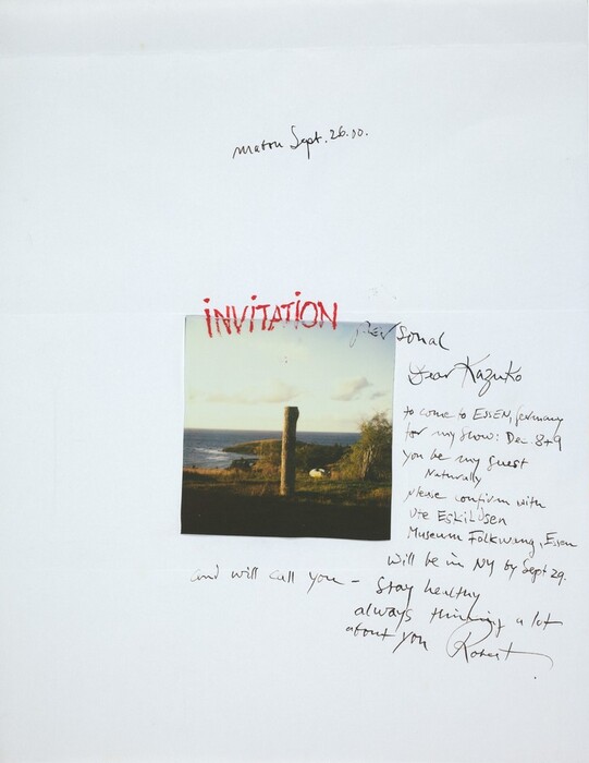 This is a photograph of a scenic landscape by the sea with handwritten notes around it. The photograph features a tall, cylindrical stone pillar set against a coastline with a body of water in the background and grassy terrain in the foreground. The sky above is partly cloudy. Surrounding the photograph are handwritten notes on a plain white paper, with text that includes date annotations, an invitation, and a personal message. The words "INVITATION" and "Personal" are prominently written. The handwriting varies in size and style.