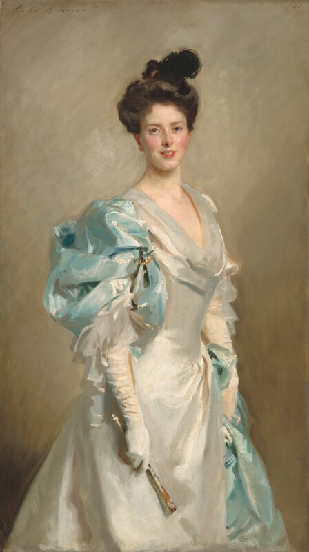 Shown from the knees up, a young woman with pale skin and flushed cheeks looks at us, wearing a long, shimmering white dress partially draped with powder-blue fabric in this vertical portrait painting. The brushstrokes are loose in her clothing but blended in her face, giving the portrait a soft, almost blurred look. Her body is angled to our right but she turns to look directly at us. Her dark, chestnut-brown hair is piled loosely on her head. A dark form could be a feather or small hat set to one side. Her eyes may be two different colors; her right eye is grayish-blue and her right eye looks almost green. She has a straight, snub nose, and her fuchsia-pink lips are parted in a small smile. There is a faint suggestion of a cleft in her pointed chin. Her white dress has a low, scooped neck and a tight-fitting bodice over a flaring skirt. Powder blue-fabric drapes over her right shoulder, closer to us, and might be pinned or pulled through a gold ring there. The blue fabric appears on her left hip, farther from us, suggesting it may wrap across her back. The sheen of the white dress and blue fabric suggests silk. The artist signed the work in cursive letters in the upper left, “John S. Sargent,” and dated it in the upper right, “1902.”