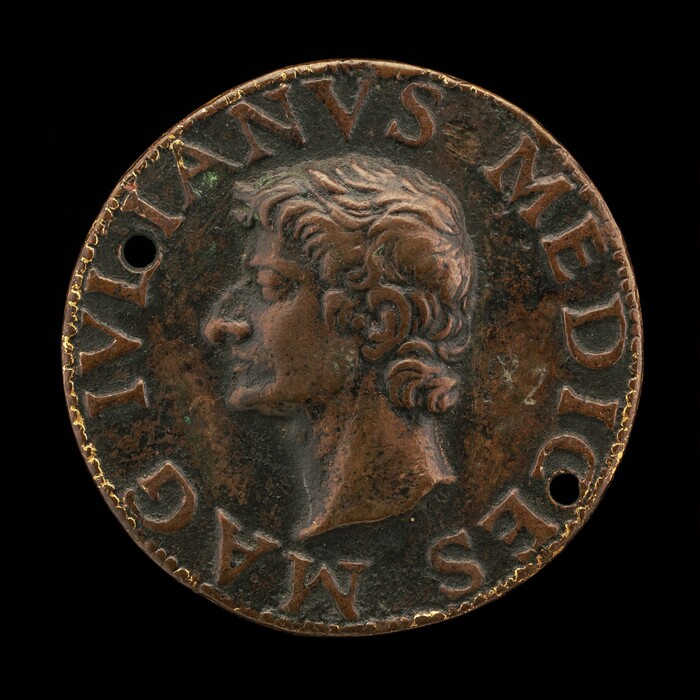 This is a photograph of a round coin with a sculpted profile of a male figure in relief, facing left. There is an inscription in classical lettering. The background of the coin is textured, and the outer edges show signs of wear and patina. Two holes are visible near the edge. The overall hue of the coin is a coppery brown.
