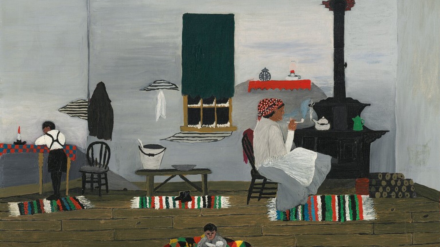 Painted with small areas of mostly flat color, this horizontal painting shows three brown-skinned people in the room of a home with pale gray walls and wood floors. To our right, a woman wears slate-gray skirt, a white apron and shawl, and a red headscarf with black and white polka dots. She sits in a black wooden chair facing our right in profile, smoking a pipe. A steaming kettle and bright green coffee pot sit on a black wood stove behind and to the right of the woman, with firewood stacked to the right. A clock or timer and an oil lamp sit on a red shelf above the stove and the woman’s head. Beneath her feet is one of three rectangular area rugs with a pattern of green, black, white, and red stripes. A window at the center of the back wall of the room is mostly covered by a dark green curtain. The panes along the bottom are black and lined with white, suggesting snow or frost. A bucket and pewter-colored, shallow bowl sit on a bench on the second striped rug under the window. To our left, a small person standing on the third patterned rug wears short black pants, stockings, and suspenders over a white shirt. That person turns away from us and rests elbows near a lit candle on a table with a red and gray checkered tablecloth. The third person, possibly a young girl, sits on a blanket or a fourth rug patterned with yellow, red, black, and green triangles. That young girl wears a gray dress and black shoes. She cradles a baby doll, and a white dog, perhaps a stuffed animal, sits next to her. A few cracks in the wall near the window expose horizontal bands, perhaps narrow wooden boards under damaged plaster. The artist signed the work with black letters in the lower right corner: “H. PiPPiN.”
