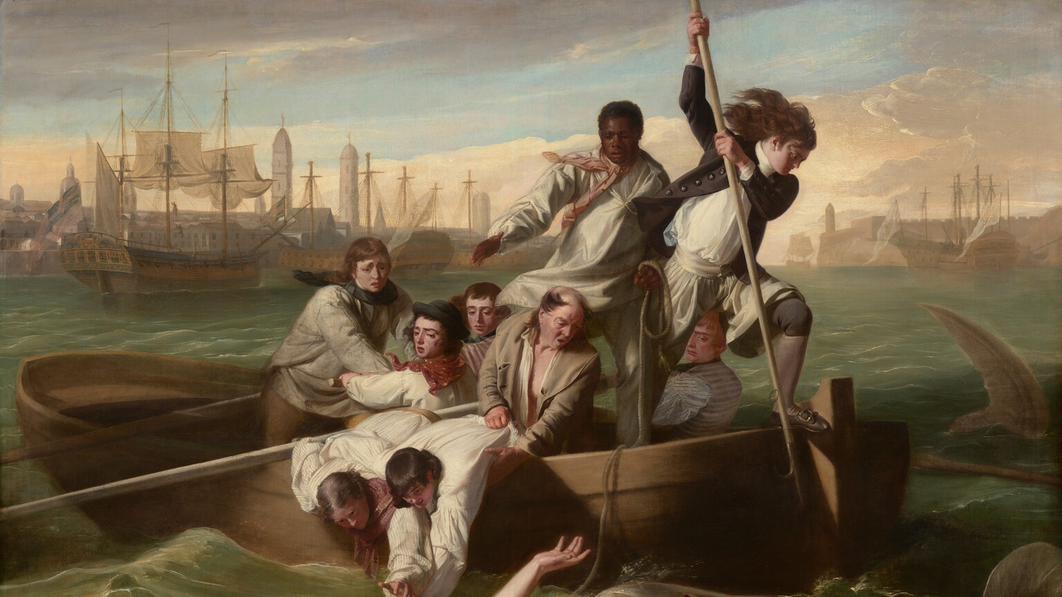 We look onto the side of a rowboat crowded with nine men trying to save a pale, nude young man who flails in the water in front of us as a shark approaches, mouth agape, from our right in this horizontal painting. In the water, the man floats with his chest facing the sky, his right arm overhead and the other stretched out by his side. Extending to our left, his left leg is bent and the right leg is straight, disappearing below the knee. His long blond hair swirls in the water and he arches his back, his wide-open eyes looking toward the shark behind him. To our right, the shark rolls up out of the water with its gaping jaws showing rows of pointed teeth. In the boat, eight of the men have light or tanned complexions, and one man has dark brown skin. The man with brown skin stands at the back center of the boat, and he holds one end of a rope, which falls across the boat and around the upper arm of the man in the water. Another man stands at the stern of the boat, to our right, poised with a long, hooked harpoon over the side of the boat, ready to strike the shark. His long dark hair blows back and he wears a navy-blue jacket with brass buttons, white breeches, blue stockings, and his shoes have silver buckles. Two other men wearing white shirts with blousy sleeves lean over the side of the boat, bracing each other as they reach toward the man in the water. An older, balding man holds the shirt and body of one of this pair and looks on, his mouth open. The other men hold long oars and look into the water with furrowed brows. The tip of a shark’s tail slices through the water to our right of the boat, near the right edge of the canvas. Along the horizon line, which comes three-quarters of the way up the composition, buildings and tall spires line the harbor. The masts of boats at port creates a row of crosses against the light blue sky. Steely gray clouds sweep across the upper left corner of the canvas and the sky lightens to pale, butter yellow at the horizon.