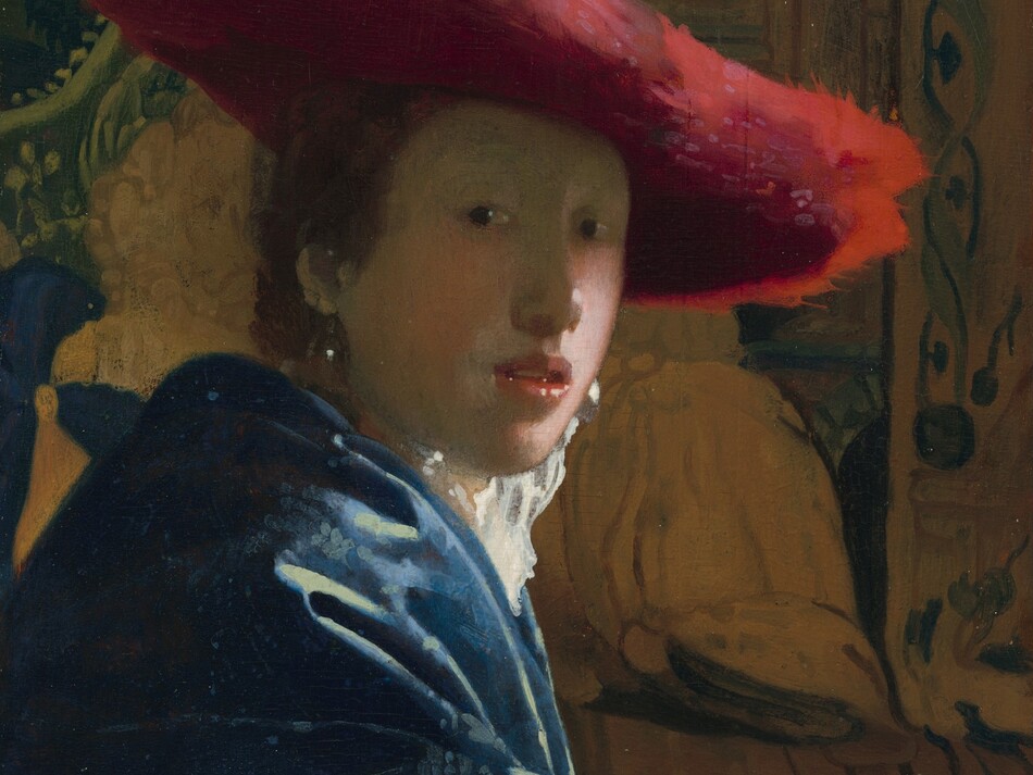 Shown from the elbows up, a young person with pale skin and brown hair wearing a wide, scarlet-red hat sits in front of a tapestry in this vertical portrait painting. She sits with her body facing our right in profile but she turns her face to look at or toward us with dark eyes. She has a rounded nose, rather flat cheeks, and a sliver of teeth is visible through parted coral-pink lips. The wide brim of the red hat seems to be made of a soft, almost feathery material, and it casts a shadow across her face. She wears a high-collared white garment that catches the light, a royal-blue, possibly velvet, robe or overcoat, and large, teardrop pearl earrings. Her arm runs along the bottom edge of the panel in front of two carved, wooden lion finials that could be the arm or back of the chair. The tapestry behind her is painted in tones of pale caramel brown and pine green. The painting has a soft, hazy look, and light glints with bright white specks off the pearl earrings, the tip of her nose, her lips, and the lion finials.