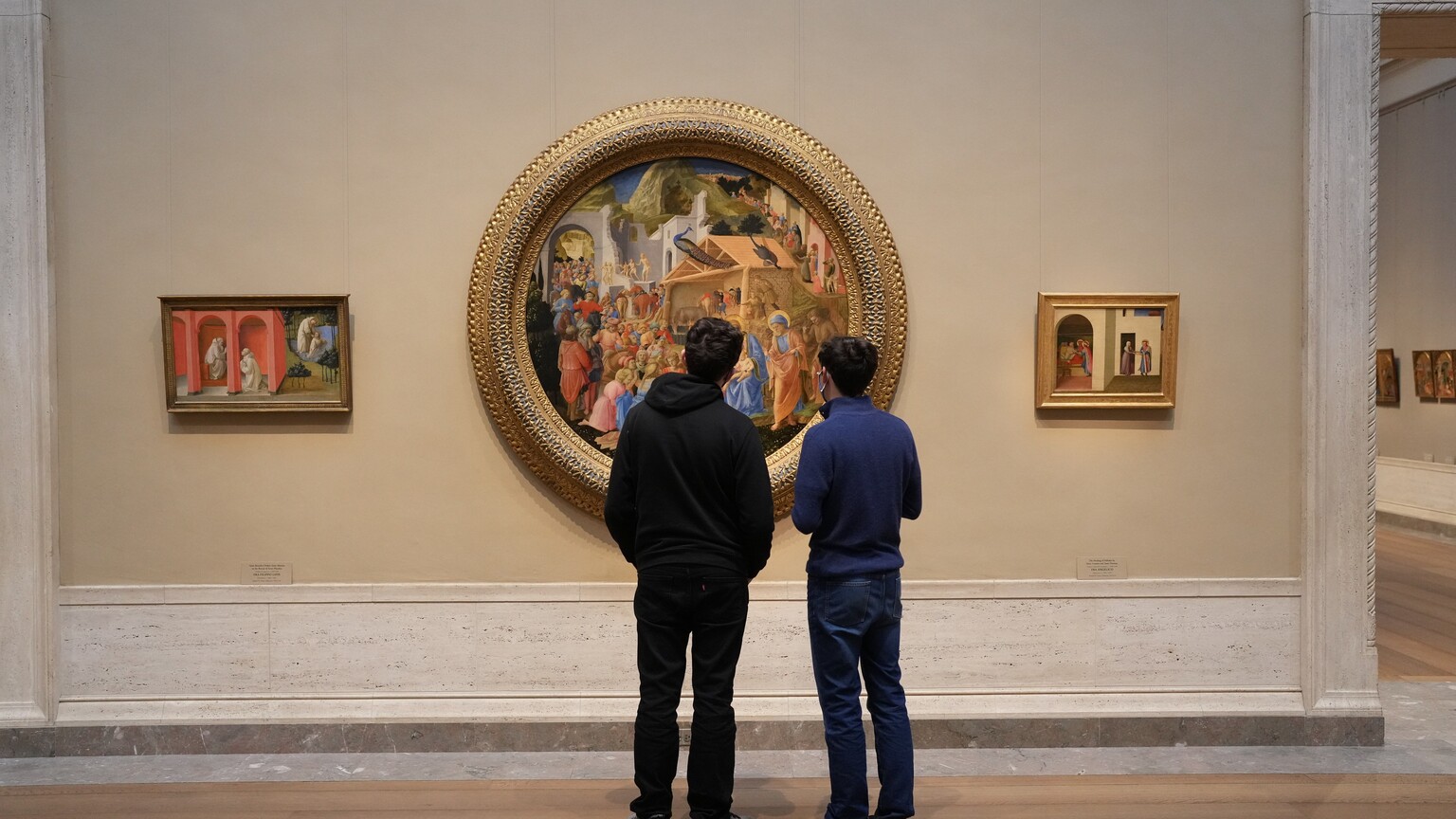 Two people looking at a circular-framed painting in the National Gallery of Art.