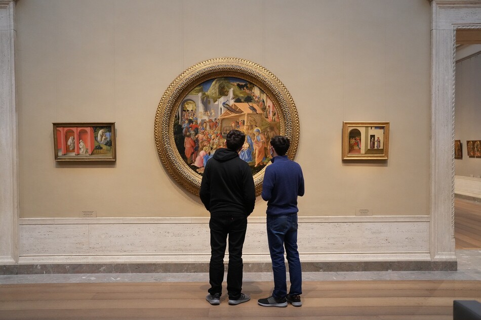 Two people looking at a circular-framed painting in the National Gallery of Art.