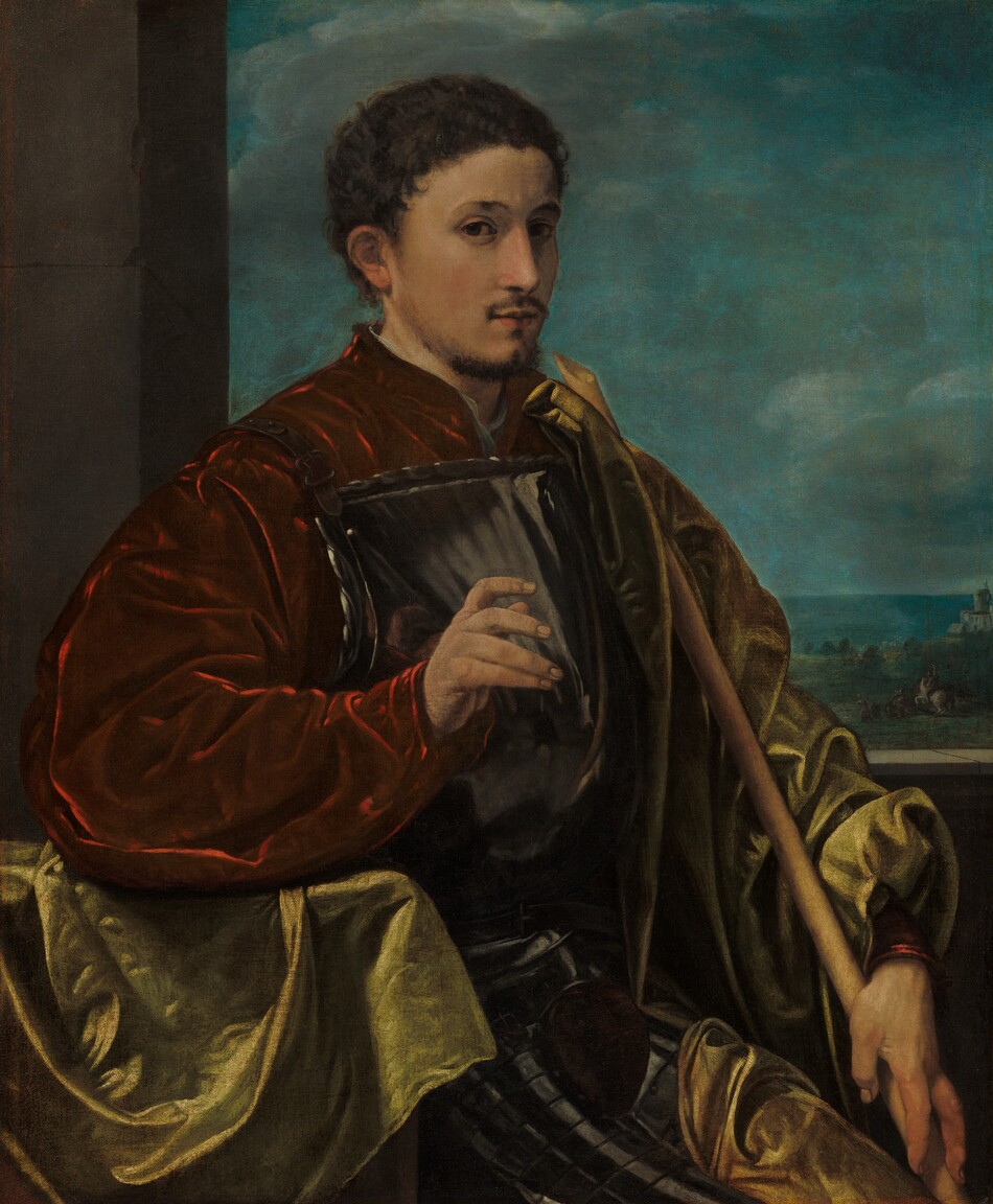 This painting shows a man from the knees up, seated and facing slightly to the right. He has pale skin, short, curly dark hair, a thin moustache, and a goatee. His expression is neutral as he gazes at us. He wears a dark red garment with voluminous sleeves, with a shining, polished gray breastplate over it. Draped over his shoulder and around his back is a light green cloak, and his legs also have silvery armor. In his left hand, he holds a long wooden staff. His other hand is raised, his fingers curled. He is positioned near a stone column or wall on the left, with a background on the right depicting a distant landscape under a blue sky, with blue fields and structures in the distance.