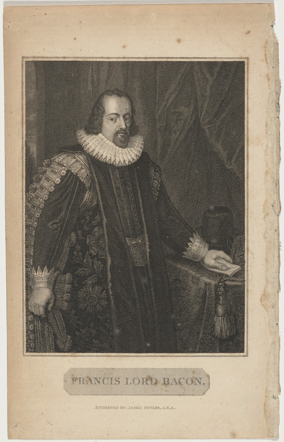 The image is a portrait engraving showing the upper body of a man standing. He has distinct facial features, with a beard, mustache, and shoulder-length curly hair. He wears a dark embroidered robe with a white lace collar, ornate details on the sleeves, and lace cuffs. He is holding a document in his right hand, resting it on a table with a patterned cloth. The background features a heavy draped curtain. A caption below the image identifies the man as "Francis Lord Bacon," engraved by James Fittler.