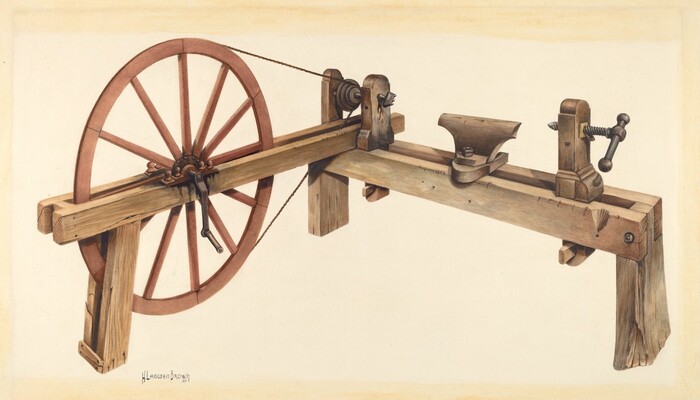 The image shows a wooden treadle-powered lathe with a large wheel on the left and a long wooden beam running horizontally across the frame. The lathe has an attached metal tool rest and a vise-like component on the right side. The color palette consists mainly of natural wood tones with some metallic grays and hints of rust on the metal parts. The large wheel is positioned on the left side of the frame, connected by a cord to the beam, while the beam stretches from the left to the right, with a metal anvil-like tool near the center.