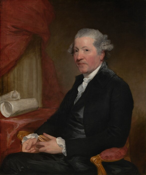 This painting is a portrait of a man shown from the waist up. He is seated, facing slightly to the left but looking directly at us. The man has light gray hair styled back from his face, with curls visible at the sides. His skin is fair with slightly pink cheeks. He is wearing a formal outfit: a dark jacket over a white, high-collared shirt with ruffled edges and dark trousers. He holds a small object, possibly a box, in his hands, which are placed in his lap. There is a red cloth or curtain behind him, with rolls of parchment or cloth on a table nearby on the left. The wall behind him is a muted green color that fades into shadow near the upper-right and lower-right corners.