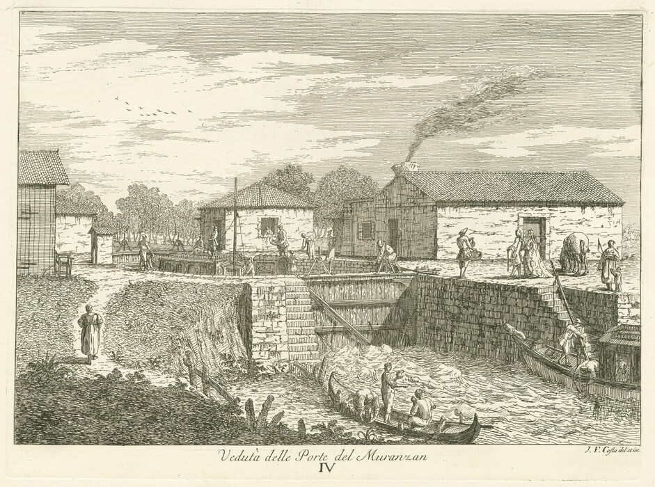 The image depicts a detailed engraving of a canal lock scene viewed from a slightly elevated perspective. Closest to the viewer are two boats in a canal, with one being guided through turbulent waters by two figures. The canal bank is built with neatly placed stones forming an embankment, and a path runs parallel to the canal where additional figures are engaged in various activities near buildings. A woman is walking along the path towards the scene. In the distance are several stone buildings with tiled roofs, one emitting smoke from its chimney. The scene suggests an industrial or residential setting. The background features a line of trees beyond the buildings. Birds are lightly depicted flying overhead in the sky, adding depth to the scene. The engraving style is precise and linear, using fine lines to detail textures like water, stone, and trees. The color palette is monochromatic, with various shades of gray and contrasting ink and paper defining elements, creating a classic, timeless quality.