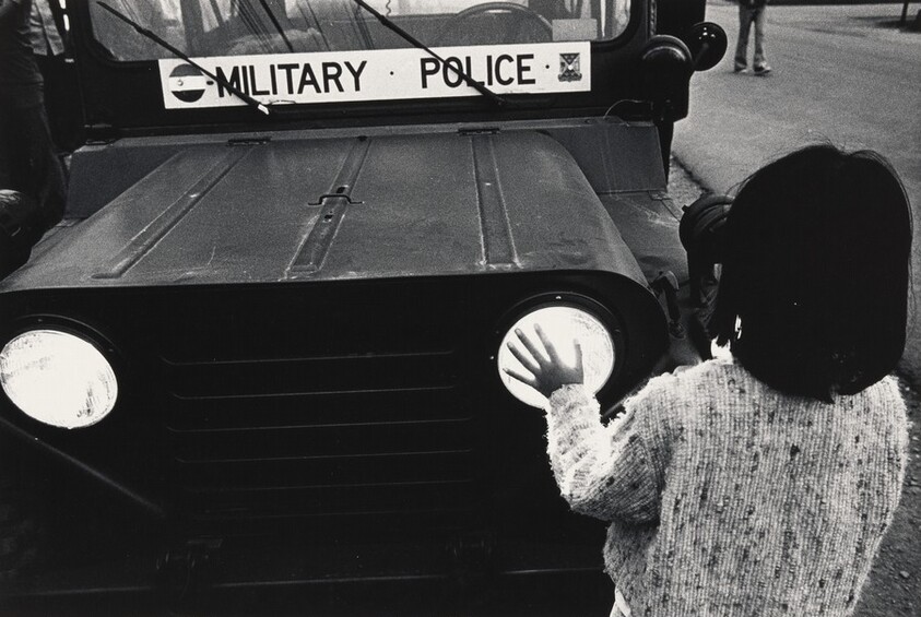 Refugee girl warming hands on headlights of Jeep