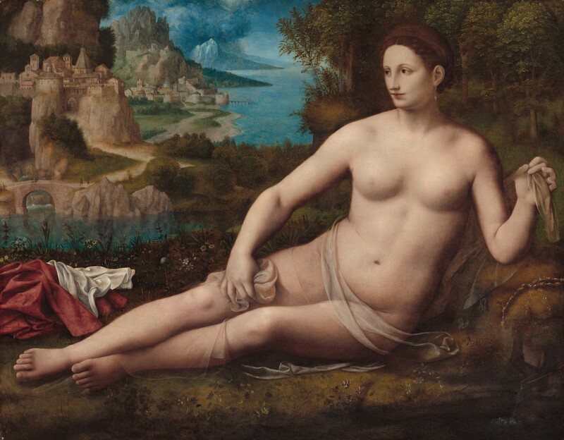 A nearly nude woman with pale, pink skin reclines along golden-yellow grass with a grove of trees behind her to our right and a landscape with rocky cliffs along a rippling shoreline to our left in this horizontal painting. Her legs extend to our left, and her body is tipped to face us, her hips stacked. Her left elbow, to our right, is propped on a swell in the ground to lift her torso. She looks off to our left with hazel-brown eyes under faint, curving brows. Her skin is smooth and shadows blur the corners of her eyes and mouth. She has a straight, long nose, and her rose-pink lips are closed. Her copper-brown hair is pulled back and up, and wraps around her head. A long, teardrop-shaped pearl hangs from the ear we can see. With both hands, she holds the ends of a translucent cloth that wraps around her hips, legs, and across her back, leaving her round, high breasts exposed. Ruby-red and white fabric lies in a heap near her feet, and a gold and pearl piece of jewelry, perhaps a necklace, drapes over the swell in the ground near her propped elbow. Small, finely detailed mauve-pink, white, or butter-yellow flowers grow in the grass around her. The land curves back along the right edge of the painting, to a grove of trees with sage and deep green leaves. An aquamarine-blue river separates her and the trees from the rocky outcroppings and towns beyond. An arched bridge spans the river and leads to a path that winds along the undulating shoreline. Buildings cluster on a rocky cliff near the bridge and a second grouping indicates another town farther along the shore. Topaz-blue clouds billow up over indigo-blue mountains in the deep distance, against a sky painted in the same jeweled blue tones.
