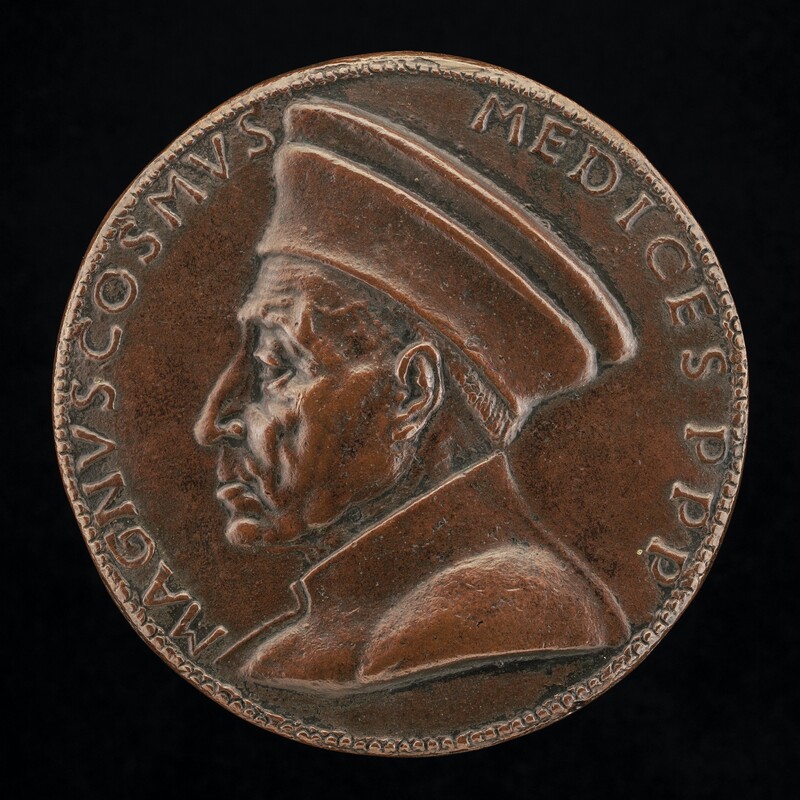 A round bronze medallion shows a man’s head and the tops of his shoulders facing our left in profile. The man has a long nose, a heavy-lidded eye, wrinkled brow, sagging jowls, and a downturned mouth. He wears a flaring, flat-topped cap and a garment with a high collar. Latin text in all caps runs lines the perimeter of the medallion, reading "MAGNVS COSMVS MEDICES P P P." The medallion is photographed against a black background.