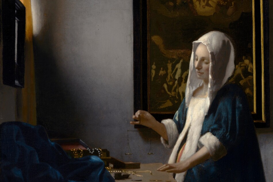 In this vertical painting, a woman stands near the corner of a dimly lit room, facing our left in profile and looking down at a balance she holds suspended in her right hand over a wooden table. She wears a peacock-blue velvet jacket with a white hood and fur lining, and a voluminous, mustard-yellow skirt. A window near the upper left corner is partially covered by a canary-yellow curtain. Light coming in through that window falls on the pale skin of the woman's face and hands, and highlights the white trim of her garment. Her left hand, closer to us, rests on the edge of the table near two open boxes, and a blue cloth is bunched at the back of the table to our left. Gold chains and pearl strands drape over the edge of one box. The woman stands in front of a framed painting. Much of the detail is lost in shadow but at the top center of the painting, a person surrounded by a golden halo floats in the sky with both arms raised, and is flanked by people encased within a bank of clouds. Nude people on the ground below in the painting, seen to either side of the woman, writhe, twist, and point upward.