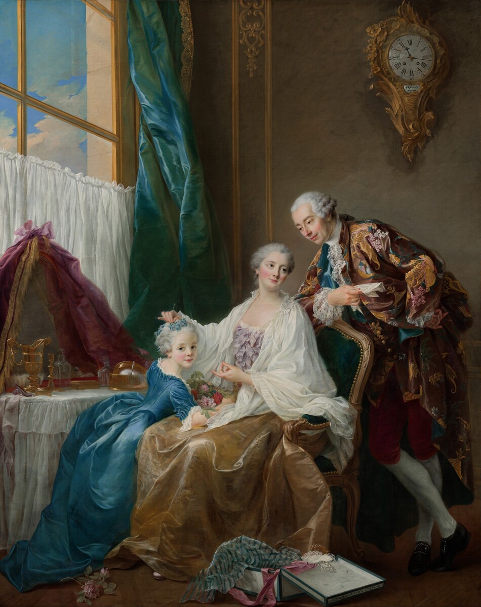 A woman sitting in an upholstered chair near a vanity table touches the hair of the little girl leaning against her lap to our left, as a man leans onto the back of her chair to our right in this vertical portrait painting. The people all have pale skin, flushed cheeks, and their pale gray hair is pulled back and curled. Their pink lips curve in slight smiles, and light glinting off of much of the fabric suggests they wear satin or silk. The woman’s body is angled to our left, toward the girl, but she turns her head back to look up over her other shoulder with gray eyes. A voluminous, cream-white cloth drapes over her shoulders and lap, over a bodice covered in lilac-purple bows and ribbons. Her gold satin skirt falls around her feet. The little girl leans onto one arm on the woman’s lap as she turns to look at us with pale blue eyes. The girl’s forget-me-not-blue dress has a fitted bodice, elbow-length sleeves over white cuffs, a long, full skirt, and white ruffles along the collar. The woman holds blue flowers in the girl’s hair, and the girl’s forearm wraps around a bundle of pink and red flowers in the woman’s lap. The chair is upholstered in teal blue and has a gold frame and a row of gold nail heads along the padded back and arm. The man leans one forearm against the back of the chair as he looks down at the girl. In that hand, he holds a folded piece of paper with writing. He wears a loose jacket decorated with gold pagodas, pink and yellow flowers, and spruce-green leaves against a brown background. Foamy white lace falls back from his cuffs and hangs down from the high white collar of his undershirt. He wears brick-red, knee-length britches, white stockings, and black shoes with silver buckles. His other hand is planted against his hip, and one ankle is crossed in front of the other. A vanity draped with a white cloth sits on the far side of the woman and girl, along the left edge of the painting. It holds gold and glass vessels and boxes, and a rounded mirror at the back is draped with dark pink cloth. The lower half of a window behind the vanity is covered by a white cloth, and the panes continue beyond the top of the canvas. A teal-blue curtain hangs along the right edge of the window, at the corner of the room. A clock with a gold case of swirling, carved designs hangs high on the peanut-brown wall behind the man. On the floor near the chair, blue and white striped tissue paper, a rose-pink ribbon, and a strand of pearls drape over the edges of an open box. Writing along the front edge of the lid of the box reads, “Fs. Drouais. Ce 1 avril. 1756.” A pink rose lies near the girl’s feet, to our left.