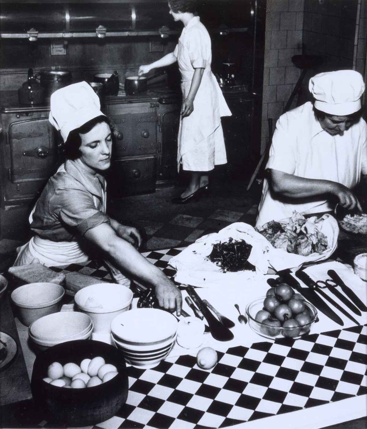 Cook and kitchen maids preparing dinner