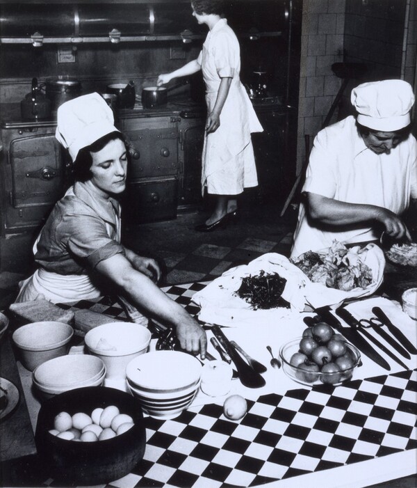 Cook and kitchen maids preparing dinner