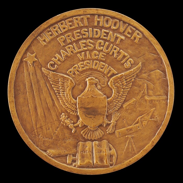 The sculpture features a round medal with a depiction of an American eagle holding arrows and an olive branch. Raised letters above the eagle read "HERBERT HOOVER PRESIDENT" and "CHARLES CURTIS VICE PRESIDENT." Additional elements include a shooting star or comet, a mountain landscape, a small building, a telescope, and an open book with text. The sculpture is in a warm, bronze or gold tone.