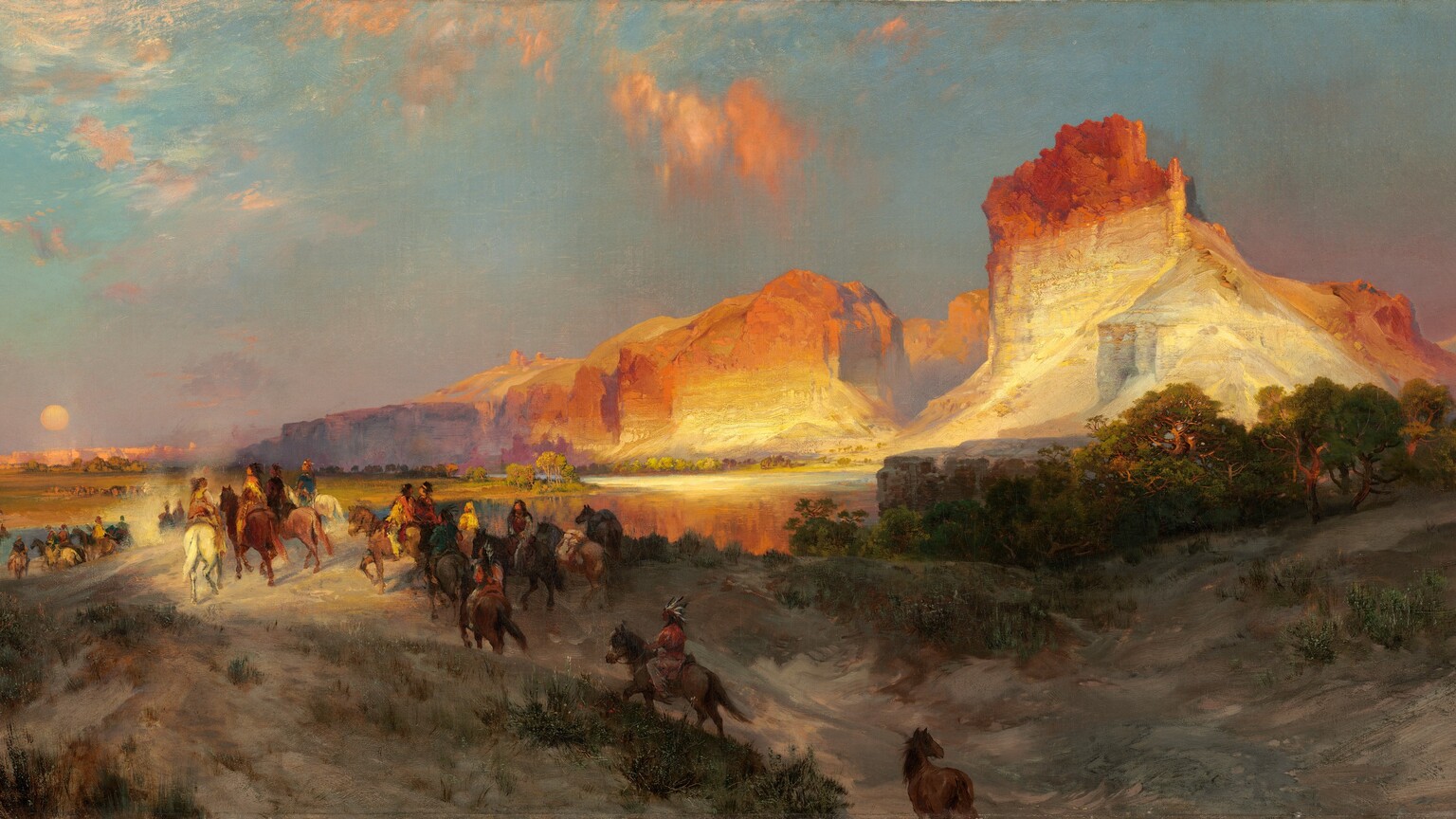 Sheer, vertical, cliffs, brightly lit in cream white and rust orange by the low sun, tower over a band of people riding horses into the distance in this long, horizontal landscape painting. The glowing cliffs dominate the upper right quadrant of the painting. They lighten from burnt orange along the jagged tops to flame orange down the steep sides, and are and warm, parchment white near the earth. One tall, narrow promontory to our right looms over a range of lower, rounded cliffs. As the cliffs move into the distance, they are shrouded with a lavender-purple haze. The land closest to us dips into a shallow valley at the bottom center of the composition, leading away from us. The dirt-packed earth is dotted with pine-green, scrubby bushes and vegetation and a grove of low, gnarled trees a short distance to our right. One chestnut-brown horse walks along the path at the bottom center of the composition, lagging behind a cluster of at least two dozen horses and riders winding into the distance. The horses range from ivory white to tawny brown and charcoal gray. The riders are loosely painted so some details are indistinct, but they all seem to have brown skin and dark hair. They wear feathered headdresses and garments in teal blue, fawn brown, or golden yellow. They ride over a low hill toward a crystal-blue river, and then back along a flat expanse toward a row of minuscule, triangular tepees lining the horizon in the deep distance. The horizon comes halfway up the composition, and the tepees are backed by a row of rose-pink, flat-topped cliffs. A pale yellow disk hangs low in the sky, over the distant cliffs. The sky above deepens from soft, lilac purple along the horizon to ice and sapphire blue along the top. A few wispy clouds are burnished orange in the sunlight. The artist signed and dated the painting in the lower right corner, “TYMoran 1881,” with the T, Y, and M overlapping to make a monogram.