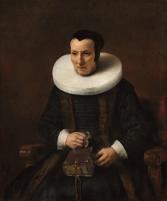 Shown from the knees up, a pale-skinned woman wearing a black dress with white cuffs and a wide, starched collar sits in a wooden chair against a dark brown background in this vertical portrait painting. Her body faces us and she looks off to our left with brown eyes. She has slight jowls at her chin and her eyes, mouth, and forehead are lined. Her hair is pulled back under a close-fitting black cap. Extending straight from around her neck, her white collar is pleated into narrow figure-eights and nearly reaches her shoulders. She wears a brown stole over her velvety black dress, and both nearly blend with the dark background. She holds a pair of pince-nez spectacles in her right hand, which rests on a thick book in her lap. The spine faces her right, and the opposite edge is fastened with metal clasps. A braided cord affixed to the narrow end of the book near us creates a loop.