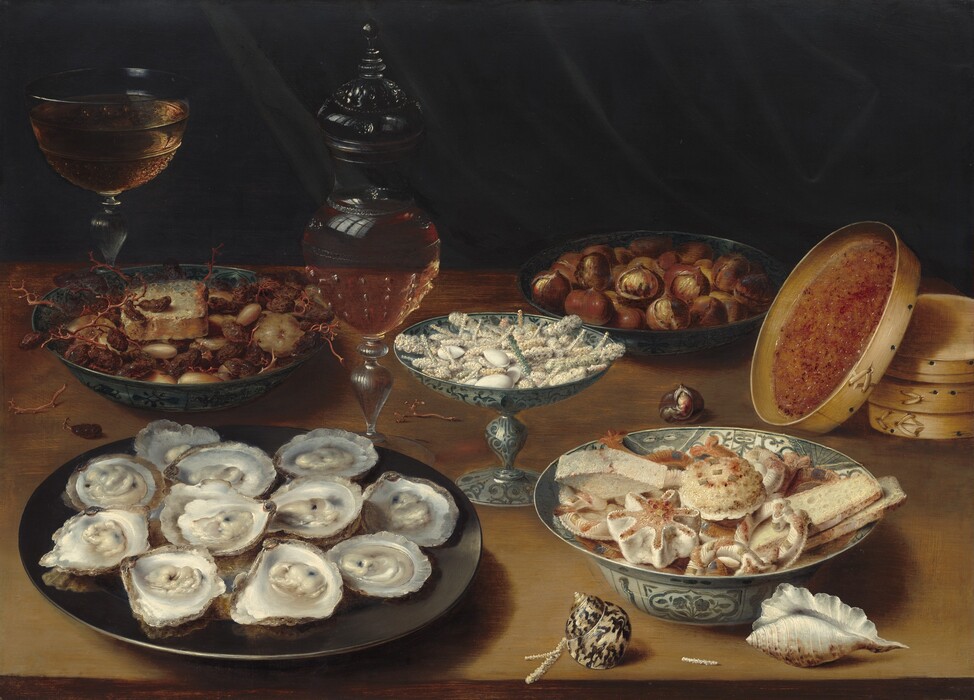 We look slightly down onto five plates, bowls, and dishes filled with oysters, raisins, prunes, figs, and sweets along with a wine glass and decanter, a stack of round, wooden boxes, and two seashells arrayed on a wooden tabletop against a dark background in this horizontal still life painting. Closest to us to our left, eleven glistening oysters on the halfshell are arranged on a round, iron-gray dish. Also close to us, to our right, a white porcelain bowl with a wide, flaring lip is painted with blue flowers, and it is piled with breads, rolls, and pastries. Two shells sit near that bowl: one shimmering, spiraling, ivory-white shell with brown marks sits to our left and an elongated, white shell with a ruffle along its length sits in the lower right corner of the panel. Between and behind these two dishes is a vessel with a pedestal foot and a wide, shallow bowl, filled with white almonds and rods that have been covered with white sugar. In the back left, a dark gray bowl holds raisins and other dried fruit along with an object that could be a slice of bread or cheese. Opposite it, a similar dish holds brown figs that more closely resemble chestnuts. To the back right, the lid of one of the three round, shallow boxes stacked along the right edge of the composition leans against the pile. The inner lid is covered with quince paste, which resembles apricot preserves. One glass goblet with a wide bowl is nearly filled with amber-colored liquid in the back left corner, beyond the dried fruit. A glass decanter, also filled with gold-colored wine, sits to our left of the pedestal-footed vessel holding the sugared sweets, at the center of the composition. The still life is brightly lit from our left.