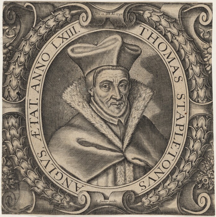 The image is an engraving showing a bust of a man, visible from the chest up, facing the viewer directly in a seated position. The man has distinct facial features with a prominent nose, pronounced cheekbones, and deep-set eyes. His expression is serious. He is wearing a large, flat hat and a fur-trimmed cloak. His hair appears short and is not prominently visible under his hat. Surrounding him is an oval frame with foliage patterns, and text along the border reading "THOMAS STAPLETONUS ANGLUS, AETAT. ANNO LXIII." The background is filled with intricate detailing.