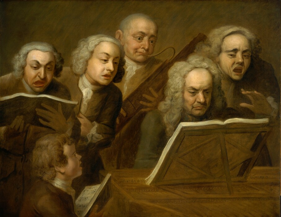 Five men and boy, all with pale skin, crowd around a book of music propped on a wooden stand on a piano or similar instrument in this horizontal painting. Light falls across the scene from high to our left. The boy is closest to us, in the lower left corner. Shown from the shoulders up, he holds an open book but looks up at the keyboardist. His lips are mouth parted and his face deep in shadow. Three of the men appear to sing, one plays a bassoon, and the keyboardist plays with grim determination, his downturned lips pressed tightly together. The keyboardist’s eyebrows are lowered under a high forehead. He wears a long, gray wig and a gray jacket. The bassoonist is over his shoulder to our left. He appears to be bald or balding and wears a frilly white cravat tucked into an ochre-yellow vest. His eyes and cheeks bulge as he plays, his lips pressed around the reeds. The brown suits of the other three men nearly blend into the wall behind them, and they all have chin-length gray hair, presumably wigs. The man to our far left glares down at a book with his dark brows arched up and away from his nose, and his lopsided mouth open wide. The man next to him leans in to look at the book in front of the pianist, and the third singer, to the far right, lifts one hand as he opens his mouth wide, his brows gathered, and his wig pushed back on his head.