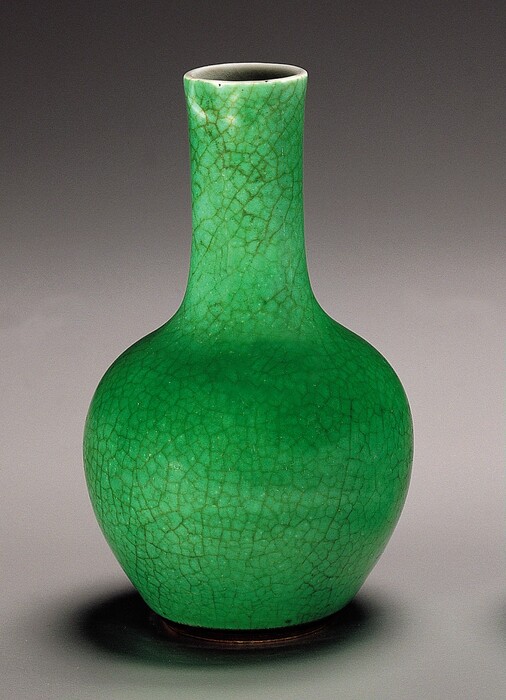 This is a large ceramic vase with a long neck and rounded body. The vase is bright green with a crackle glaze pattern that creates thin, branching cracks across its surface. The lip at the top is white, and the interior appears black.
