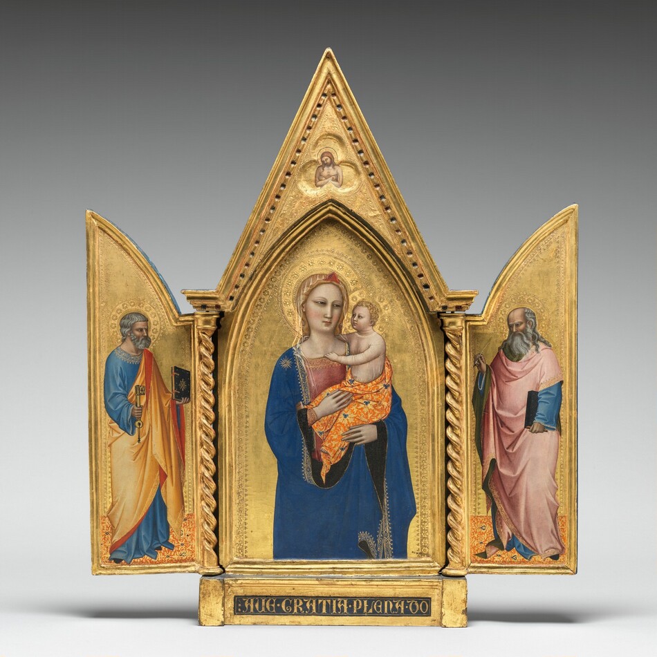 Two panels on a gilded, carved, wooden frame are swung open like shutters to show a bearded, gray-haired man wearing robes standing in each wing, on either side of panel with a pointed, arched top showing a woman holding a baby. In a three-lobed shape in the apex above the woman and child, a nude man crosses his arms over his chest. All the people have pale, ivory-colored skin. Gold halos encircle each person’s head and the background of all three panels is bright gold. The woman in the center panel is shown from the hips up with her body facing us. The deep blue mantle that drapes over her shoulders and her dusty rose-pink dress beneath are trimmed in gold. A sheer veil covers her wavy blond hair and a red, triangular form sits above her forehead like a diadem. She looks to our right with dark, almond-shaped eyes. She has a straight nose, her coral-pink lips are closed, and her smooth cheeks are lightly flushed with pale pink. She holds the child in the crook of her left arm, on our right, and rests her other hand in the baby’s lap. He has short, curly blond hair and looks directly at the woman. He reaches his right arm, farther from us, around his mother’s neck and hooks his other hand in the neckline of her dress. He wears a sheer shirt edged in gold, and the fabric draped around his hips is patterned with tangerine-orange and gold, with lapis-blue clover designs. He has rounded cheeks and a pudgy tummy, but his facial features and arms are scaled more like an adult. Twisted columns separate this central panel from the shutter-like panels to each side. A single person stands in each wing, filling most of the space, and both are angled and look towards the central panel. Both men have darker, olive-toned complexions, wear long robes trimmed in gold, and stand on floors patterned with orange, gold, and sparsely spaced royal blue diamond-shapes. The man to our left has short, steel-gray hair and a trimmed beard. Wrinkles line his forehead, and his brow is furrowed. He wears a topaz-blue, long sleeved garment under a honey-orange robe, the underside of which is ruby-red where it turns back over his wrists and shoulder. He holds a book with a dark cover up in his left hand, farther from us, and a large skeleton key in his other hand. In the right panel, a balding man has a fringe of long, gray hair and a flowing, full beard. His forehead is also creased with wrinkles and his brow is furrowed. The dark, olive-green lining of his rose-pink robe shows where it folds back at his neck, over his wrists, and down the front. His robe covers a topaz-blue garment as well. He holds a book, also with a dark cover, by his side with his left hand, closer to us, and holds up a feather quill with his opposite hand. The inner edges of each of the central panel and both wings are incised with bands of decorative floral and geometric designs punched into the gold backgrounds. In the pointed peak above the central panel, the nude man is shown from the waist up in a three-lobed, clover shape that would be visible even if the wings were closed. The man’s body faces us but his haloed head tips to his right, our left. He has a beard and long brown hair, and a hole dripping blood pierces the back of his left hand, visible on our right. The base of the tryptic is inscribed with gold letters in a dark field: “AVE GRATIA PLENA DO.”