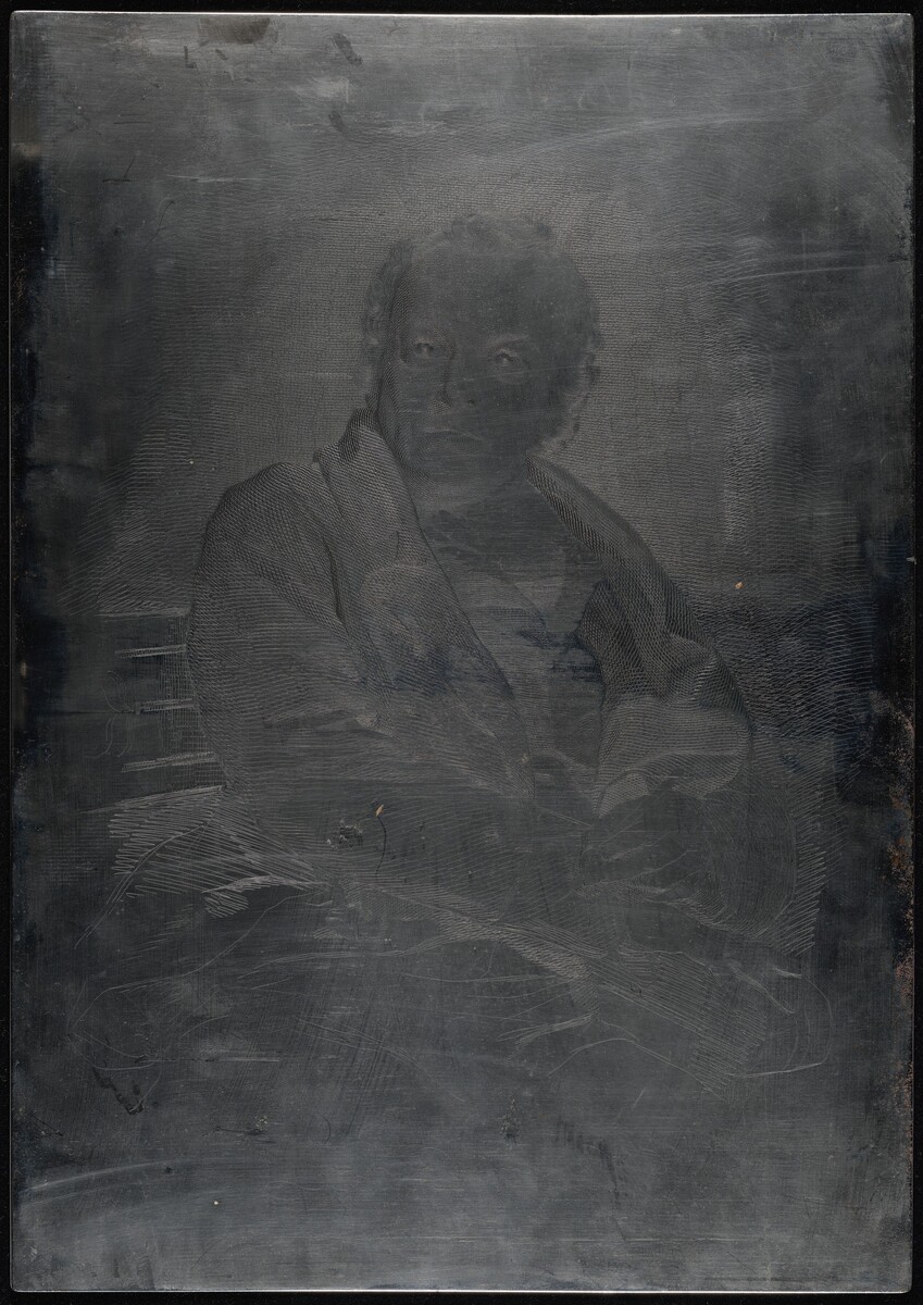 This is a photograph of an engraved metal plate. The image shows a metal surface that has been engraved with fine lines and details depicting an individual. The surface is dark, and the engravings highlight the contours and features of the figure with intricate line work. The lines are meticulously etched, producing a ghostly visage that subtly emerges from the metal's surface.