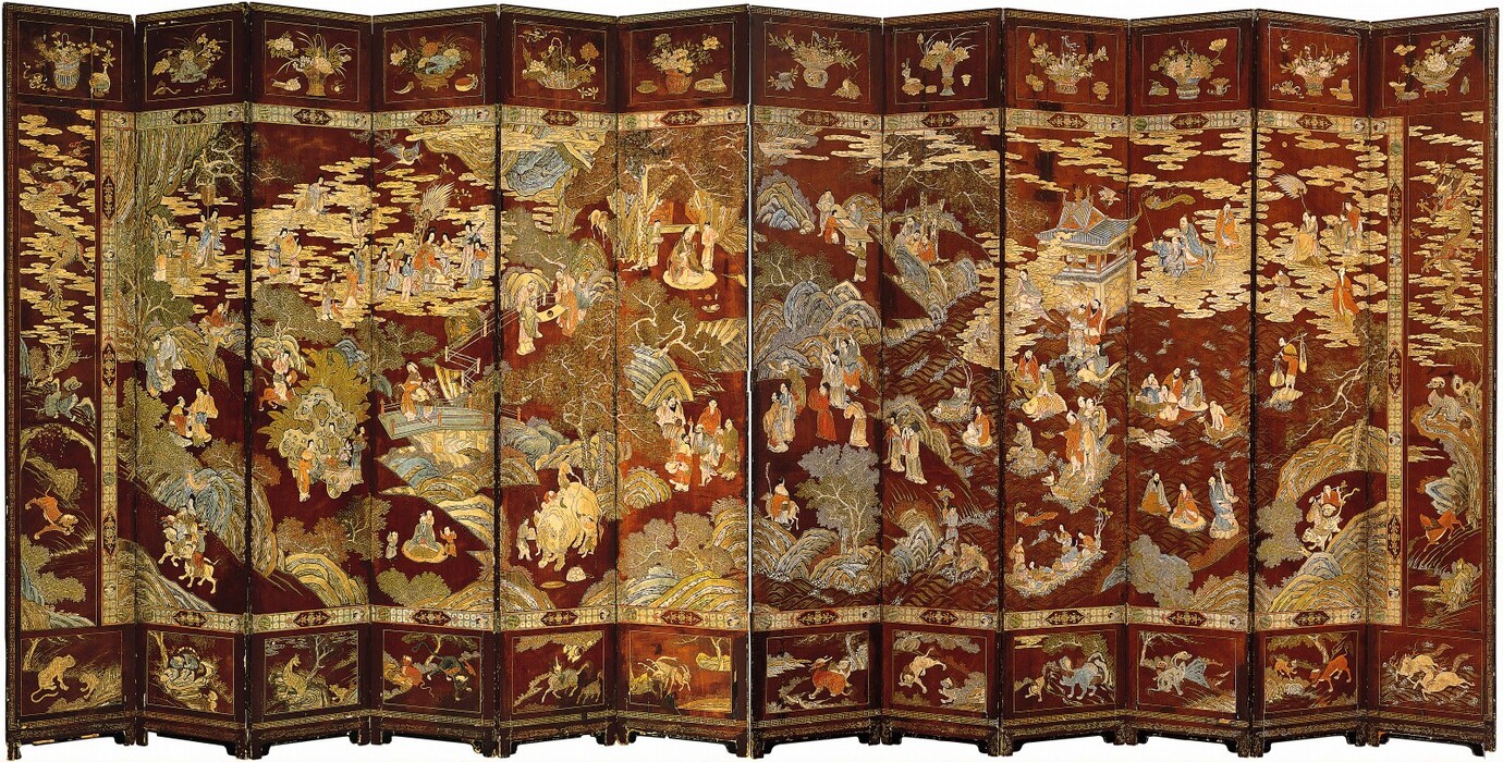 This is a painted folding screen with multiple panels showing numerous people engaged in various activities within a lush green setting. The screen features rich reds, golds, blues, and greens. The people wear draped clothing in bright colors, and they are interacting with each other amidst ornate buildings, bodies of water, rocky hills, and vegetation, with fantastical animals appearing throughout. Each panel contributes to a scene that spans across the entire screen. The background of the panels is a rich reddish-brown.