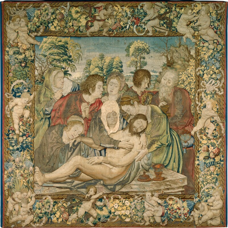 Five women and three men gather around the limp, nude body of a man being laid on a stone slab in this square tapestry. The people’s skin is pale, nearly ivory white. The torso of the dead man, Jesus, is being supported by two women, one of whom wraps her arms around his shoulders. The man has a brown beard and hair, and his eyes are slightly open. He has holes in the hand and foot we can see and a gash over his right ribs. A silvery blue cloth is between Jesus and the stone surface, where a copper-colored ointment jar sits with the lid off near the front right corner. The woman embracing him has a white head covering and lapis-blue and white dress. The other woman supporting his torso, to our right, wears a dress that shimmers between frosty lemon-lime green and cobalt blue. Her strawberry blond hair is braided, wrapped around her head, and ornamented with pearls. A third woman to our left bends over and touches Jesus’s far hand to her cheek. She and the others standing in a row behind this group wear robes in tones of slate blue, pale green, blue, and rose red, though some areas appear gray with damage or wear. Behind Jesus and these three women are two more women and three men. They all look on except one woman and man, who look at a chalice a man standing to the right holds. That man has a long gray beard and hair, and a pouch hangs at his waist. The man next to him holds a ring of thorns. The landscape beyond the group has trees with yellow-highlighted and blue-shaded trees and distant buildings and mountains under a blue sky. The scene is framed by an ornamental design of chubby, pale-skinned baby boys playing games amid fruit, flowers, and ribbons. Two boys at the top play with hobby horses. To the right, one child feeds another as a third plays with a stick and chest-high hoop. A boy blows bubbles in the lower right corner, and another plays a drum nearby. A boy with rings of bells wrapped under his knees runs toward the drummer. Two in the lower left corner have captured a bird, and another above them walks on stilts.