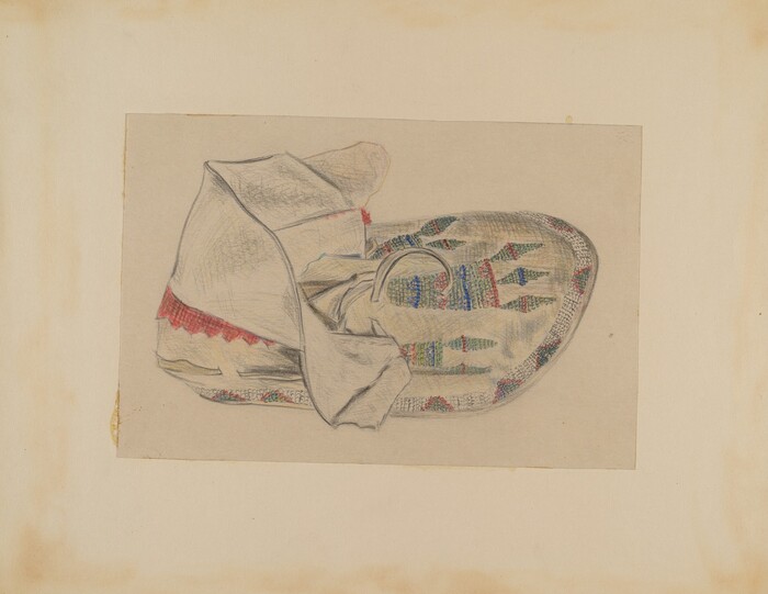 The image shows a white cloth covering a colorful, intricately patterned object. The patterns on the object include geometric shapes in colors like blue, green, red, and yellow. The background is plain and neutral.