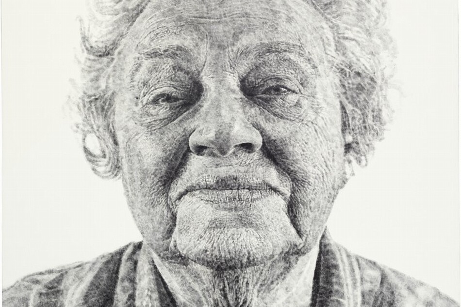 Shown from the shoulders up against a white background, an elderly woman gazing at us fills this black and white vertical portrait painting. The portrait is created with tones of light and silvery gray with darker gray in the shadows. Short, wavy, flyaway hair stands off the top and sides of her head, and she looks at us with half-closed, small eyes under arched brows. Her wide mouth is closed, and the corners are pulled back in a slight smile. Deep wrinkles run down from the corners of her mouth to her drooping jowls. There is a deep, round hollow, shaded black, at the base of her neck, which is surrounded by a starburst of fine wrinkles. She wears a light gray, V-neck shirt with white stripes and stylized flowers. The overall impression is that this portrait is painted with delicate tones of gray, but closer inspection reveals that it was made with inked fingerprints. The whorls of fingers in black ink, pressed lightly or layered against the canvas, are visible.
