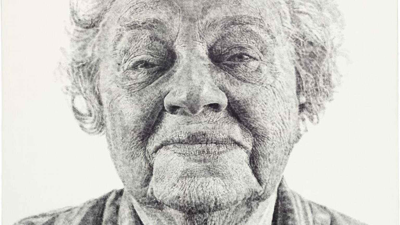 Shown from the shoulders up against a white background, an elderly woman gazing at us fills this black and white vertical portrait painting. The portrait is created with tones of light and silvery gray with darker gray in the shadows. Short, wavy, flyaway hair stands off the top and sides of her head, and she looks at us with half-closed, small eyes under arched brows. Her wide mouth is closed, and the corners are pulled back in a slight smile. Deep wrinkles run down from the corners of her mouth to her drooping jowls. There is a deep, round hollow, shaded black, at the base of her neck, which is surrounded by a starburst of fine wrinkles. She wears a light gray, V-neck shirt with white stripes and stylized flowers. The overall impression is that this portrait is painted with delicate tones of gray, but closer inspection reveals that it was made with inked fingerprints. The whorls of fingers in black ink, pressed lightly or layered against the canvas, are visible.