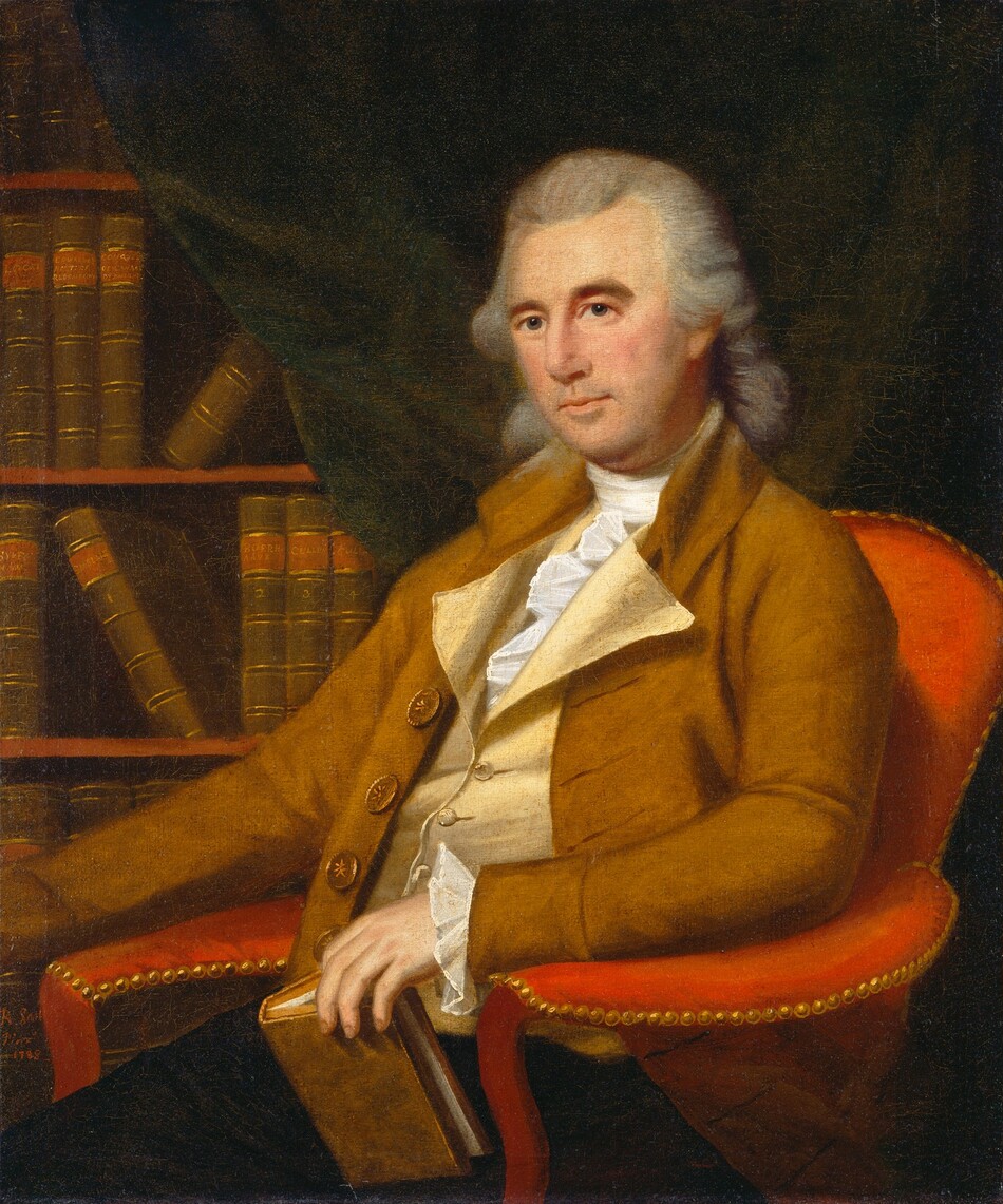 The image shows an upper-body portrait of a seated man. He is positioned in an angled chair, facing slightly to his right. His facial features include a composed expression, a narrow nose, and focused eyes, with a prominent forehead framed by his powdered, shoulder-length hair. The man is dressed in a brown coat with large buttons over a pale waistcoat and a white, ruffled shirt. He holds a book in his left hand, resting it on the arm of the chair. The chair is upholstered in red fabric with a gold-studded trim. In the background, there is a bookcase filled with books, partially visible. The dark drapery provides contrast and depth to the setting.